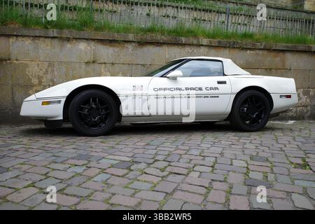 Bad Bentheim, Germania - 4 maggio 2025 Una Chevrolet Corvette C4 bianca è parcheggiata accanto a un vecchio muro. È stata una Pace Car ufficiale Indianapolis nel 1986 Foto Stock