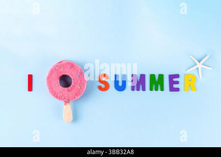 Vacanze estive e vacanze concetto con gelato sotto forma di salvagente di ciambelle rosa, con l'iscrizione i Love Summer. Su sfondo azzurro Foto Stock