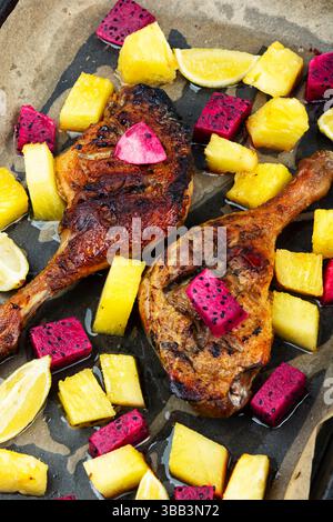 Cosce d'anatra appena tostate confit con ananas, lime e frutta di drago in teglia da forno. Foto Stock