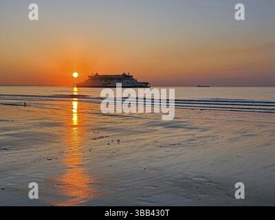 Tramonto sulla spiaggia con una nave e un caldo cielo arancione, Oceano Atlantico, Calais, Francia, Europa Foto Stock