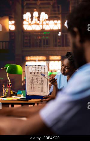 Il team infermieristico del futuro apprende l'anatomia umana in una biblioteca del campus, esamina i corsi e prepara gli esami. Studenti della scuola di medicina nera che lavorano insieme per le loro carriere mediche. Foto Stock