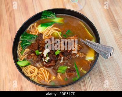 Zuppa di manzo con spaghetti e verdure su fondo di legno Foto Stock