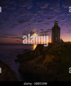 Half Moon Bay, CA - 6/10/2024: Il Faro di Pidgeon Point , è in costruzione di notte, con una luna luminosa che illumina la scena. Foto Stock