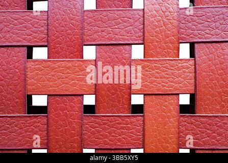 Primo piano dettagliato di un motivo in pelle intrecciata rossa con superficie testurizzata, perfetto per sfondi, design o temi di moda. Foto Stock