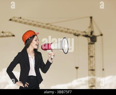 Donna-costruttore in elmetto con megafono Foto Stock