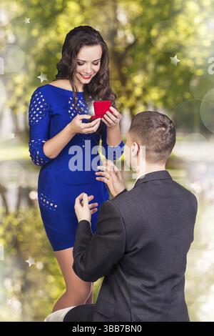 Il giovane fa una proposta alla sua ragazza in ginocchio Foto Stock