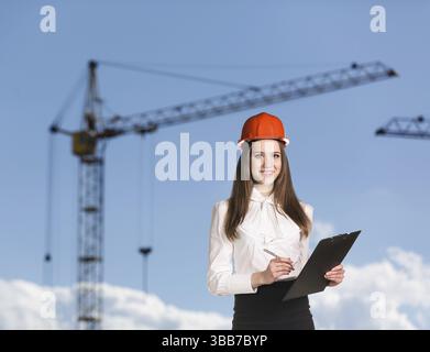 Donna sorridente con elmetto sul lato dell'edificio Foto Stock