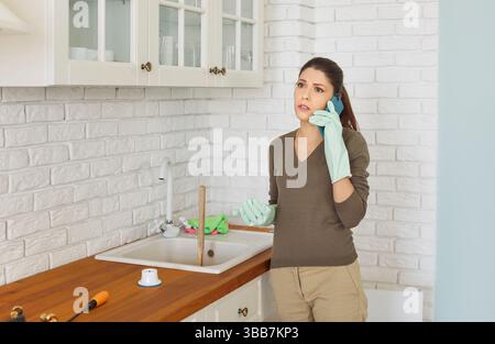 Abbiamo chiamato il servizio idraulico, il lavandino della cucina era intasato, la casalinga si lamentava al telefono Foto Stock