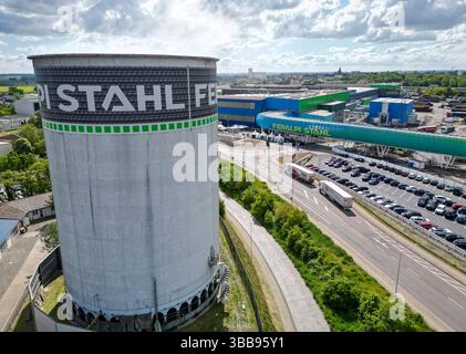 15 maggio 2025, Sassonia, Riesa: Veduta dell'Elba-Stahlwerke Feralpi. Le acciaierie di Riesa si concentrano su tecnologie più rispettose del clima con un nuovo laminatoio. Lo stesso giorno è stato inaugurato un nuovo laminatoio, che produce acciaio nel cosiddetto "ambito 1" senza emissioni dirette di CO2. In totale, Feralpi ha investito più di 220 milioni di euro nel sito - secondo l'azienda, il più grande investimento singolo nella sua storia tedesca. L'espansione creerà circa 100 nuovi posti di lavoro, portando la forza lavoro a circa 950 dipendenti. (Vista aerea con drone) foto: Jan Woitas/dpa Foto Stock
