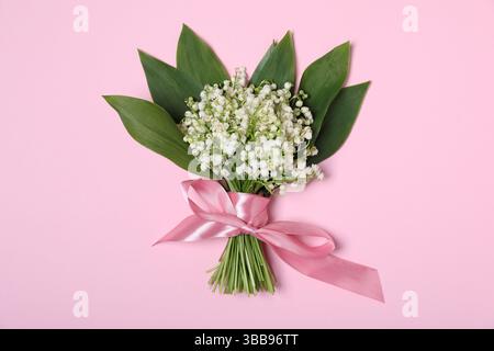 Splendidi fiori di giglio della valle su sfondo rosa chiaro, vista dall'alto Foto Stock