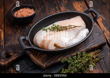 Filetto di merluzzo crudo incontaminato, in attesa di essere marinato e cucinato alla perfezione per una deliziosa esperienza culinaria. sfondo in legno. vista dall'alto. Foto Stock