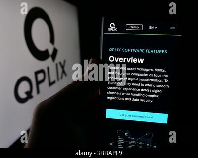 Stoccarda, Germania - 12-27-2024: Persona che detiene uno smartphone con sito web della società tedesca di software di gestione patrimoniale QPLIX GmbH sullo schermo con logo. Foto Stock