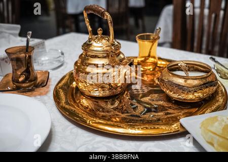 Vista ravvicinata del tradizionale set da tè arabo mediorientale tradizionale, tazze di vetro d'epoca con teiera sul tavolo del ristorante. vin precedente Foto Stock