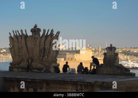 I giovani viaggiano in Europa, vista posteriore in estate di tre giovani che guardano attraverso il Porto grande nella città di la Valletta, Malta Foto Stock