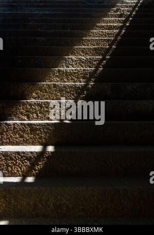 Scale in pietra con fascio di luce e ombra dal sottopassaggio Foto Stock