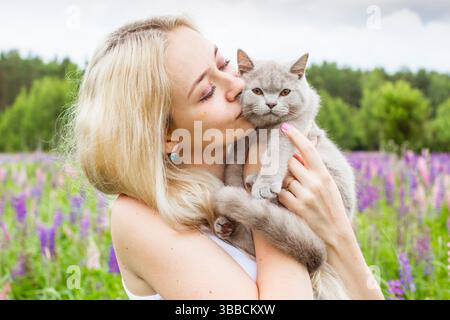 mosca, russia, 13.07.2017 Una donna sta tenendo un gatto tra le braccia. Il gatto è grigio e ha un naso rosa. La donna sorride e si sta godendo la mamma Foto Stock