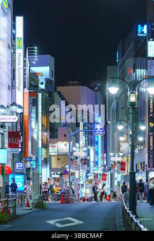 Tokyo, Giappone - settembre 30 2024, vista verticale di una stretta strada pedonale con grattacieli coperti da pubblicità e cartelloni con illuminazione, Foto Stock