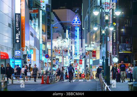 Tokyo, Giappone - settembre 30 2024, vista panoramica di una stretta strada pedonale con grattacieli coperti da pubblicità e cartelloni con illuminazione Foto Stock