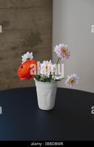 Piccolo bouquet di piccole dimensioni in vaso di ceramica bianca su un tavolo nero Foto Stock