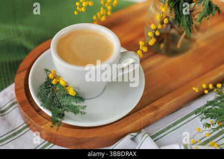 Tazza di caffè bianco con fiori di mimosa in una mattina di primavera Foto Stock