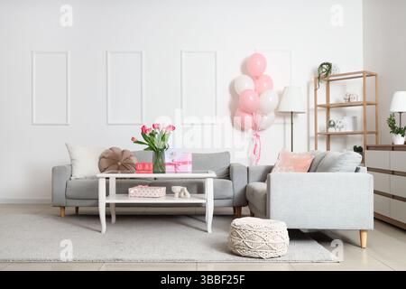 Interno del soggiorno arredato per la festa della donna con divani, tavolo e palloncini Foto Stock