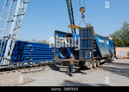 Caricamento del tubo in ghisa nel camion per il trasporto con carroponte. Foto Stock