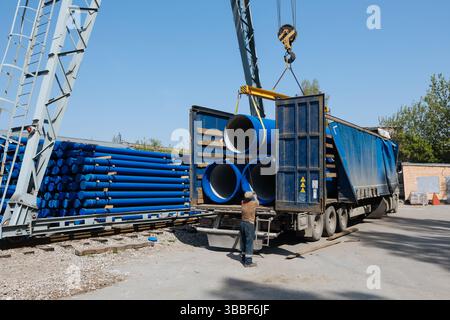Caricamento del tubo in ghisa nel camion per il trasporto con carroponte. Foto Stock