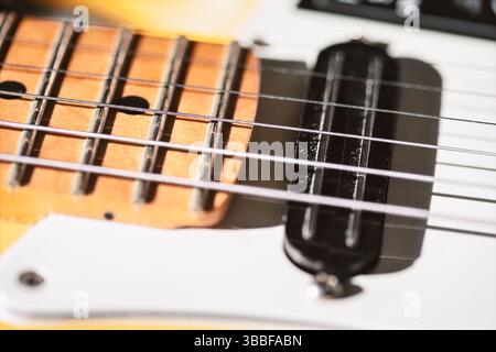 Vista di un fretboard giallo per chitarra elettrica, che mostra frets e corde in metallo con sottacapane nero. La profondità di campo bassa evidenzia la trama Foto Stock