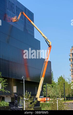 Lavoratori su un Cherry Picker (piattaforma aerea) che lavorano sul cartello del display elettronico presso la Co-op Live Arena, Etihad Campus, Manchester, Inghilterra, Regno Unito Foto Stock