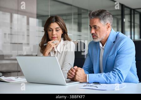 Team aziendale composto da due professionisti impegnati che lavorano insieme utilizzando un computer laptop. Foto Stock