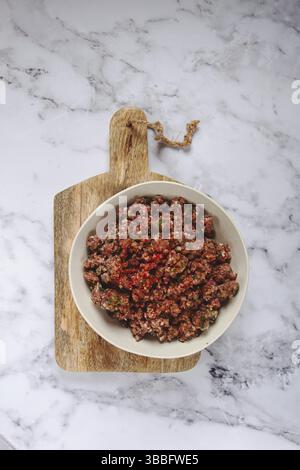 Carne macinata cruda, marinata con spezie ed erbe aromatiche, in un recipiente, carne macinata con spezie, vista dall'alto, fatto in casa, nessuno Foto Stock
