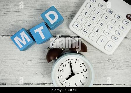 Testo MTD (Month to Date) con sveglia e calcolatrice su sfondo in legno Foto Stock