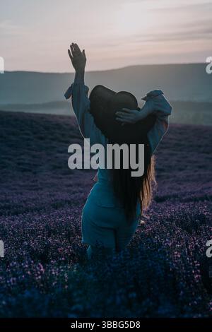 Donna in un campo di lavanda al tramonto Foto Stock