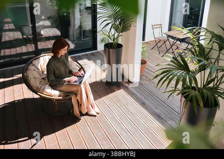 Giovane donna d'affari che usa un computer portatile che lavora su una sedia in un ufficio ecologico. Vista dall'alto Foto Stock