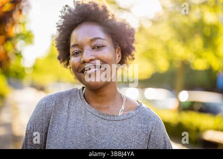 Sorridente giovane donna nel parco in una giornata di sole Foto Stock