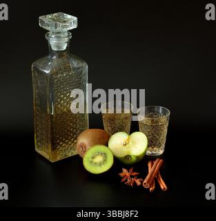 Kiwi fatti in casa e liquore di mele verdi con cannella e anice in vetro cristallo su sfondo nero. Primo piano. Foto Stock