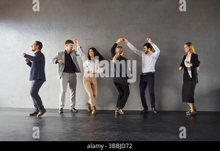 Felice felice felice felice felice, giovane e variegata, dipendenti che ballano di gruppo, lavoratori che rilassano i colleghi della compagnia di ballo Foto Stock