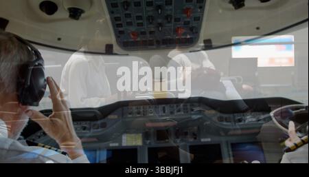 Cabina di pilotaggio in cabina jet aziendale, due piloti in uniforme che utilizzano cuffie e acceleratori Foto Stock
