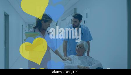 Spingendo senior in sedia a rotelle che indossa abito ospedale giù corridoio, con cartina e forme del cuore Foto Stock