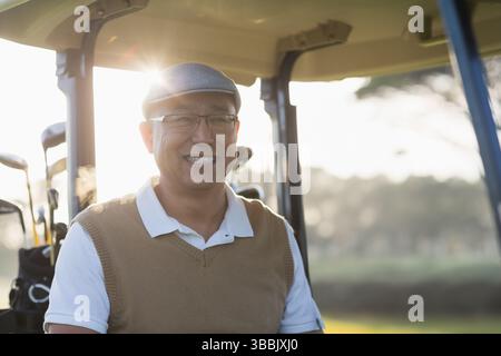 Il golf cart si trova su un fairway ben curato sotto il caldo sole del tardo pomeriggio, con mazze da golf Foto Stock