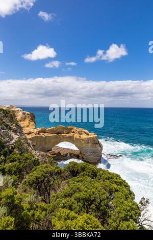 Le scogliere si innalzano sulle acque turchesi e le onde si infrangono sotto la formazione rocciosa The Arch lungo la Great Ocean Road, offrendo vedute mozzafiato Foto Stock