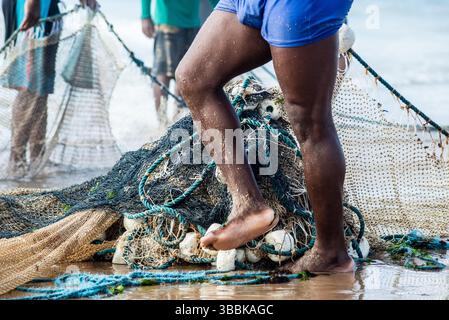Mezzo corpo di pescatori non identificati che raccolgono la rete da pesca dopo la cattura del pesce. Pesce, pesca come hobby. Brasile Foto Stock