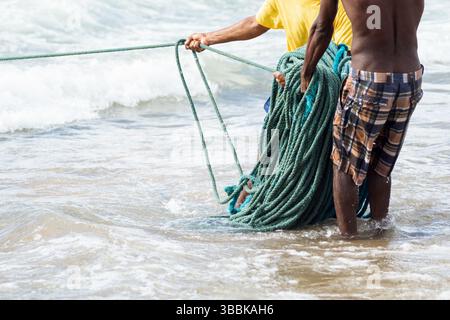 Mezzo corpo di pescatori non identificati che raccolgono la rete da pesca dopo la cattura del pesce. Pesce, pesca come hobby. Brasile Foto Stock