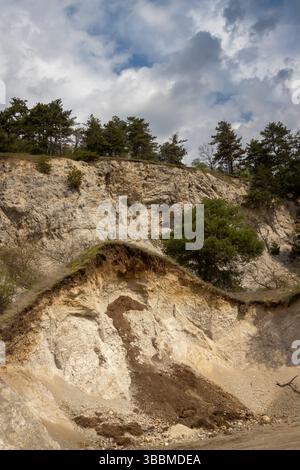 Parte rimanente di una collina, dove si trova una cava di arenaria. Conifere che crescono sulla collina. Cielo blu con intense nuvole bianche. Trstin, Repub slovacco Foto Stock