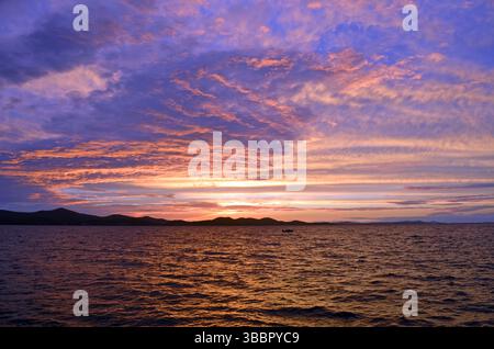 Zara, Croazia: Splendida vista sul mare al crepuscolo con colori vivaci al tramonto, nuvole luccicanti e sagome sul mare Adriatico Foto Stock