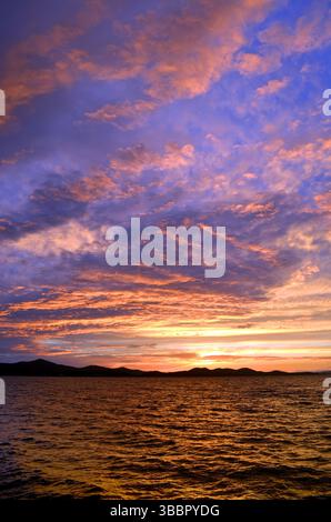 Zara, Croazia: Splendida vista sul mare al crepuscolo con colori vivaci al tramonto, nuvole luccicanti e sagome sul mare Adriatico Foto Stock