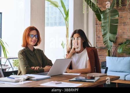 Due donne d'affari felici partner di giovane e mezza età al lavoro, ritratto. Foto Stock