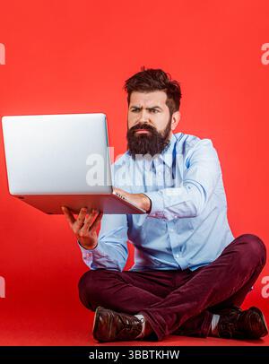 Uomo dipendente laptop. Barba che tiene un computer portatile. Giovane uomo d'affari che usa il suo computer portatile e il suo pc Foto Stock
