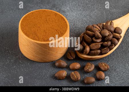Chicchi di caffè con una ciotola di caffè macinato su sfondo nero Foto Stock