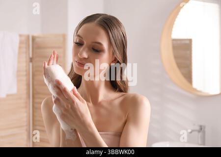 Bella donna con sapone in schiuma in bagno Foto Stock